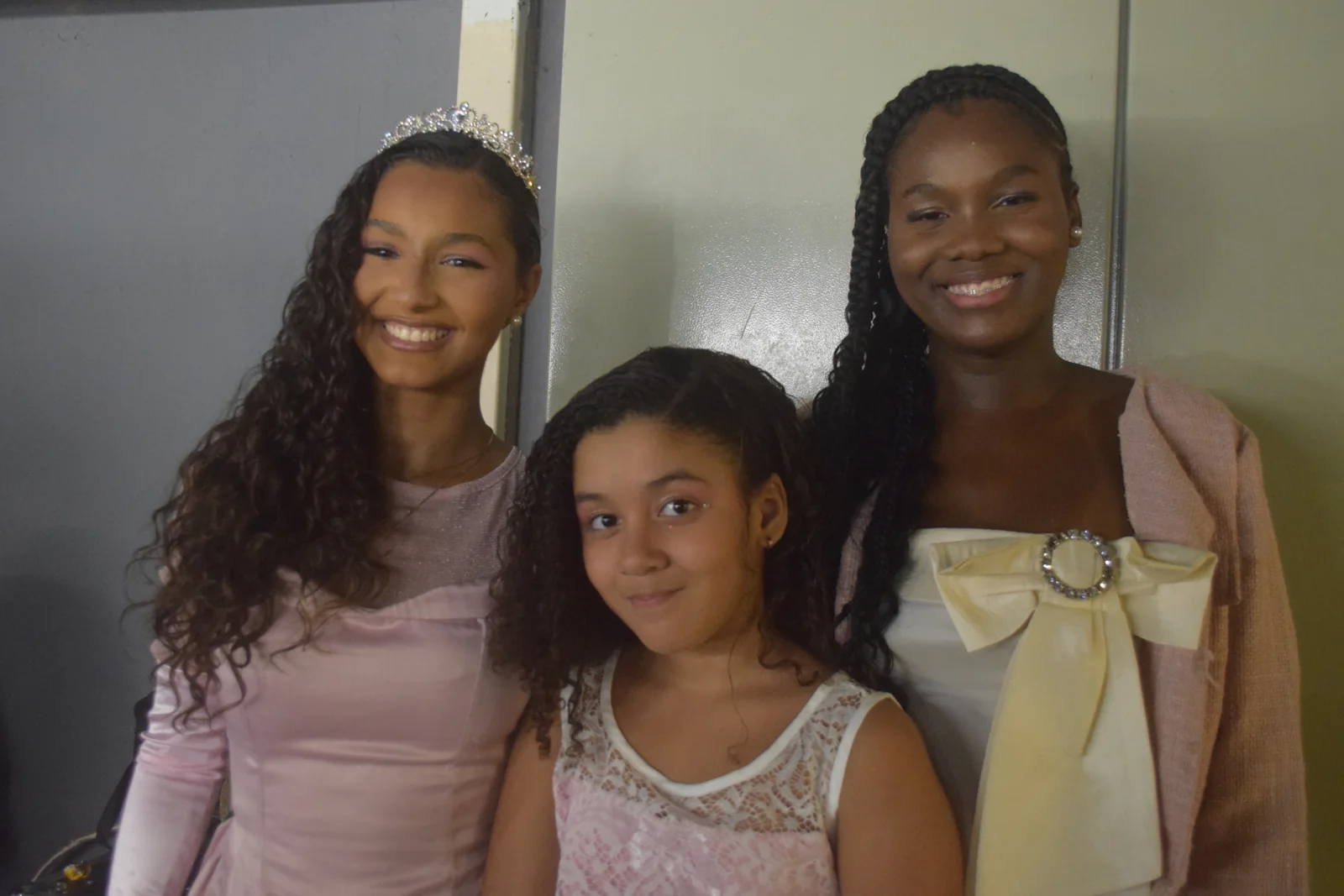 Três participantes sorrindo nos bastidores